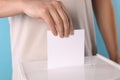 Man putting his vote into ballot box on light blue background, closeup Royalty Free Stock Photo