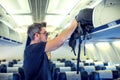 Man putting luggage on the top shelf on airplane Royalty Free Stock Photo