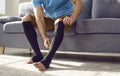 Man putting on medical compression stockings on legs for the prevention of varicose veins.