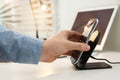 Man putting mobile phone onto wireless charger at white table, closeup. Modern workplace accessory Royalty Free Stock Photo