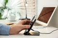 Man putting mobile phone onto wireless charger at table, closeup. Modern workplace accessory Royalty Free Stock Photo