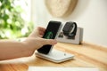 Man putting phone onto wireless charger at wooden table, closeup. Modern workplace accessory Royalty Free Stock Photo