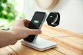 Man putting mobile phone onto wireless charger at table, closeup. Modern workplace accessory Royalty Free Stock Photo