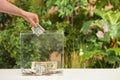 Man putting money into donation box on table against blurred background, closeup. Royalty Free Stock Photo