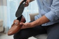 Man putting orthopedic insole into shoe indoors, closeup. Foot care