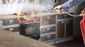 Man putting out burning stove and oven with fire extinguisher in kitchen, closeup Royalty Free Stock Photo