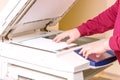 Man putting paper sheet on printer for scanning. Office work concept. Royalty Free Stock Photo
