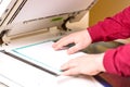 Man putting paper sheet on printer for scanning. Office work concept. Royalty Free Stock Photo