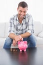 A man putting a pennie in a piggy bank Royalty Free Stock Photo