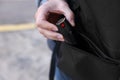 Man putting pepper spray into backpack outdoors, closeup. Space for text Royalty Free Stock Photo