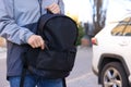 Man putting pepper spray into backpack outdoors, closeup. Space for text Royalty Free Stock Photo