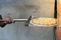 Man putting pizza baking sheet in oven at restaurant kitchen. Royalty Free Stock Photo