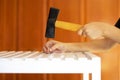 Man putting a screw into a piece of furniture with a hammer.