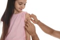 Man putting sticking plaster onto girl`s arm on white background