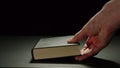 Man Putting A Thick Black Book On A Black Surface Royalty Free Stock Photo