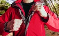 Man putting on travel hiking red jacket in woods Royalty Free Stock Photo