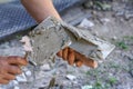 Man putting wet paste cement mortar mix on masonry trowel with metal spattle, one hand blurred to emphasise action, closeup detail Royalty Free Stock Photo