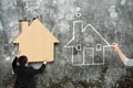 Man putting wooden house into hole of concrete wall Royalty Free Stock Photo