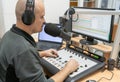 Man radio DJ sitting at the remote with headphones in the working position