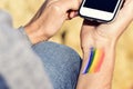 Man with a rainbow flag in his wrist using a smartphone Royalty Free Stock Photo