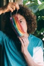 Man in a rainbow medical mask. Young guy with long curly hair wearing painted surgical mask on face. Pride protection.