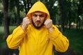 Man in raincoat puts on a hood in rainy day