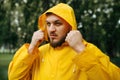Man in raincoat puts on a hood in rainy day