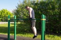 A man raises his body on two bars on a sports field on the street
