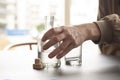 Man reaches out for a bottle of alcohol and an empty glass by the side at a table in home or bar environment. Selective focus on h Royalty Free Stock Photo