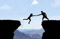 Man reaching hand to woman jumping over abyss.