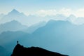 Man reaching summit after climbing and hiking enjoying freedom and looking towards mountains silhouettes panorama in Royalty Free Stock Photo