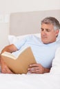 Man reading book in bed Royalty Free Stock Photo