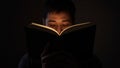 Man reading book in dark room illuminated by pages light Royalty Free Stock Photo