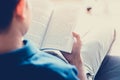 Man reading book while sitting on the couch - vintage tone