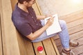 Man reading book sitting outside in public space. Wearing glasses alone working. Concept of education or busyness Royalty Free Stock Photo