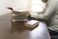 man reading book with textbook stack on wooden desk Royalty Free Stock Photo
