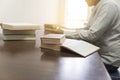 man reading book with textbook stack on wooden desk Royalty Free Stock Photo