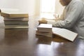 man reading book with textbook stack on wooden desk Royalty Free Stock Photo