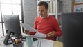 Man reading documents in office setting showing focused middle-aged work environment with computer and papers, highlighting mature Royalty Free Stock Photo