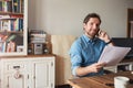 Man reading documents and talking on a cellphone at home Royalty Free Stock Photo