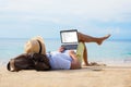 Man reading email on laptop while relaxing on beach Royalty Free Stock Photo