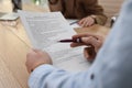 Man reading employment agreement at table in office, closeup. Signing contract