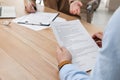 Man reading employment agreement at table in office, closeup. Signing contract