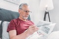 Man reading newspaper while lying in bed at home Royalty Free Stock Photo