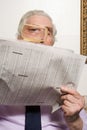 Man reading newspaper with magnifying glass