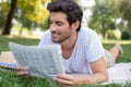 man reading newspaper while sitting on green meadow Royalty Free Stock Photo