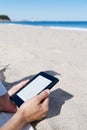 Man reading in a tablet or e-reader on the beach Royalty Free Stock Photo