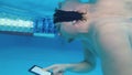 Man reads an electronic book underwater. Special waterproof electronic device. You can read the text and show signs