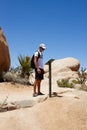 Man reads information on the trail stand. Curiosity, travel, adventure. Arch Rock, Joshua Tree National Park, CA, USA Royalty Free Stock Photo