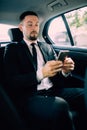 Business Man in rear of the car. Typing text message on cell phone Royalty Free Stock Photo